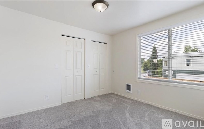 A room with a carpeted floor, two doors, and a window with blinds.