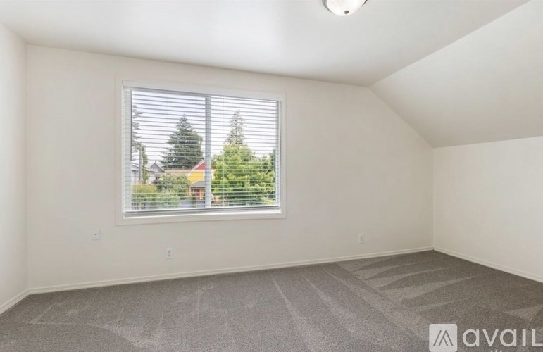A room with a window showing a view of trees and a house.