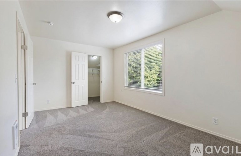 A spacious room with a carpeted floor and a window with blinds.