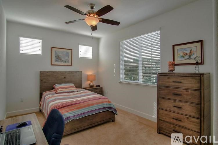 A bedroom with a bed, dresser, and a ceiling fan.