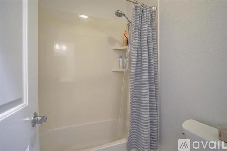 A bathroom with a shower curtain and a white tub.