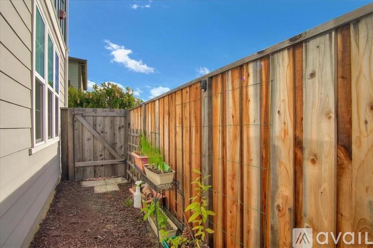 A wooden fence with a gate and plants in front of a house.