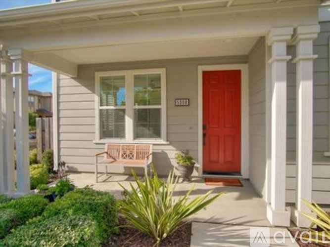 A house with a red door and a bench outside.
