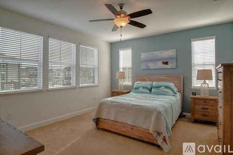 A bedroom with a bed, dresser, and ceiling fan.