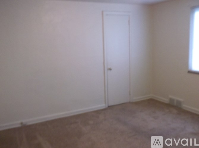 A room with a carpeted floor and a white door.