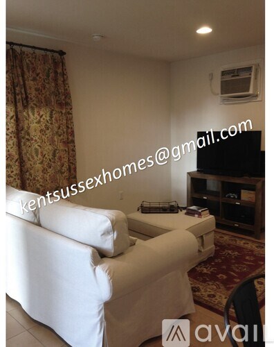 A living room with a white couch and a television.