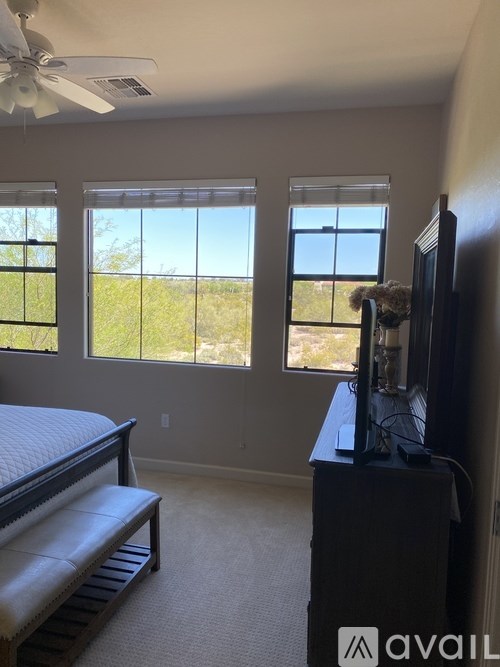 A bedroom with a bed, a television, and a window overlooking a field.