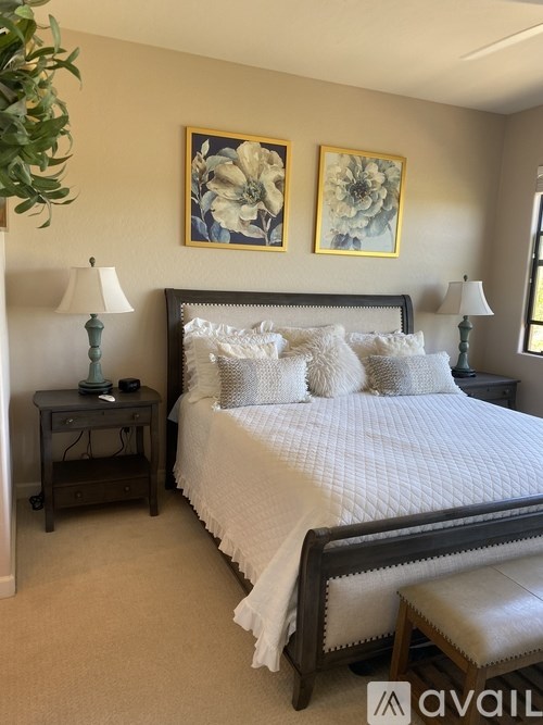 A bedroom with a large bed and two lamps.