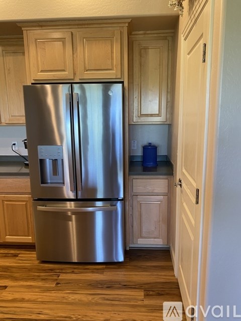 A stainless steel refrigerator in a kitchen with wooden cabinets.