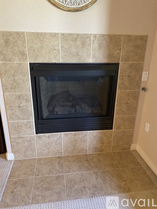 A fireplace with a black grate and a beige tile surround.