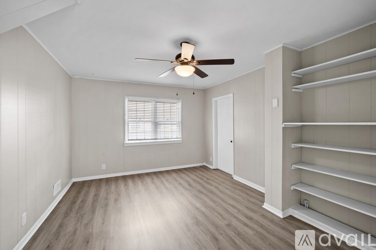 A room with a ceiling fan and a window with blinds.