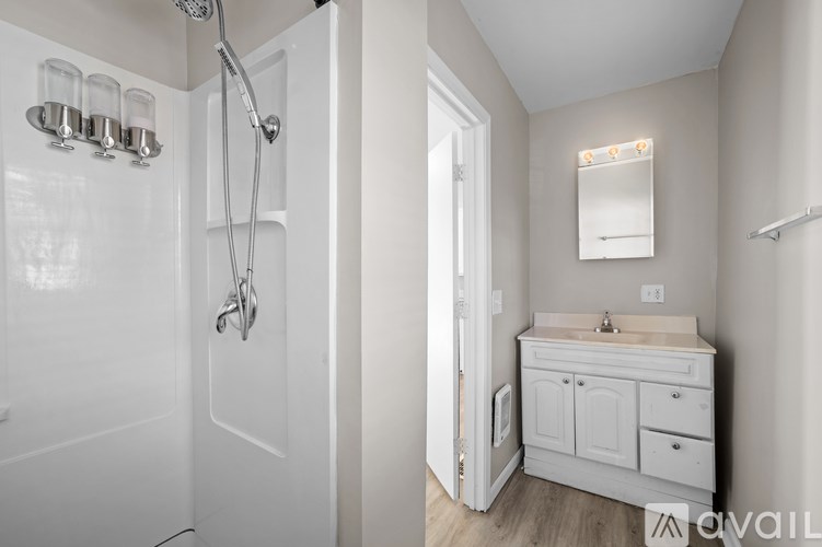 A white bathroom with a sink, mirror, and shower.
