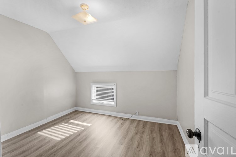 A room with a wooden floor and a window with blinds.