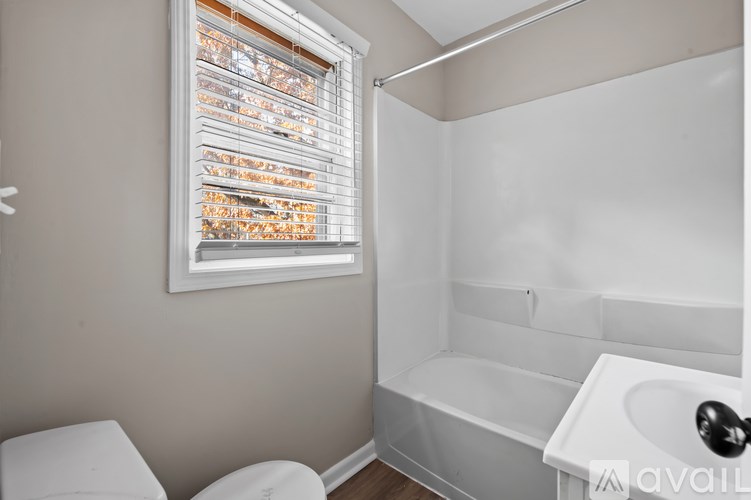 A white toilet sits next to a window in a small bathroom.