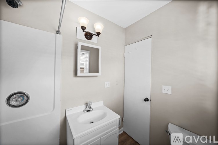 A small white bathroom with a sink, toilet, and shower.
