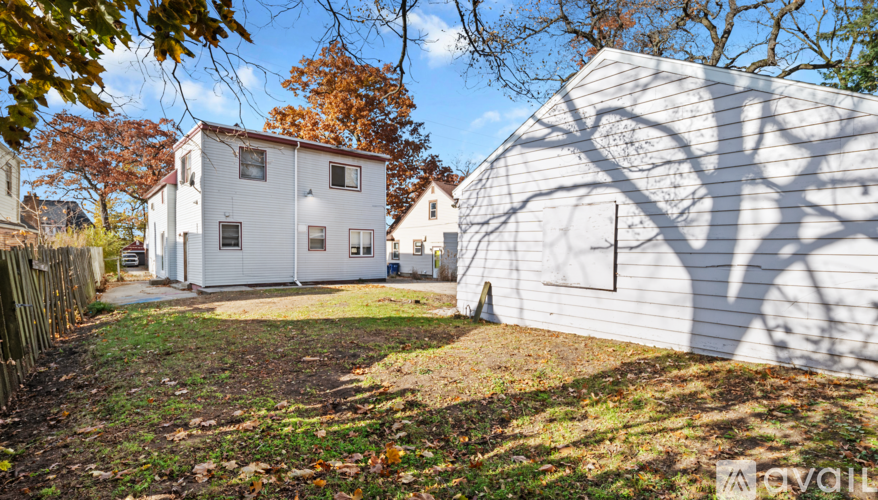 A white house with a shadow of a tree on its side.