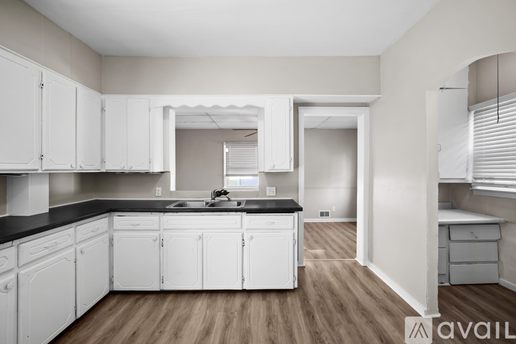 A kitchen with white cabinets and a black countertop.