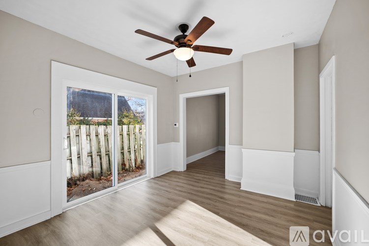 A room with a ceiling fan and sliding glass doors.