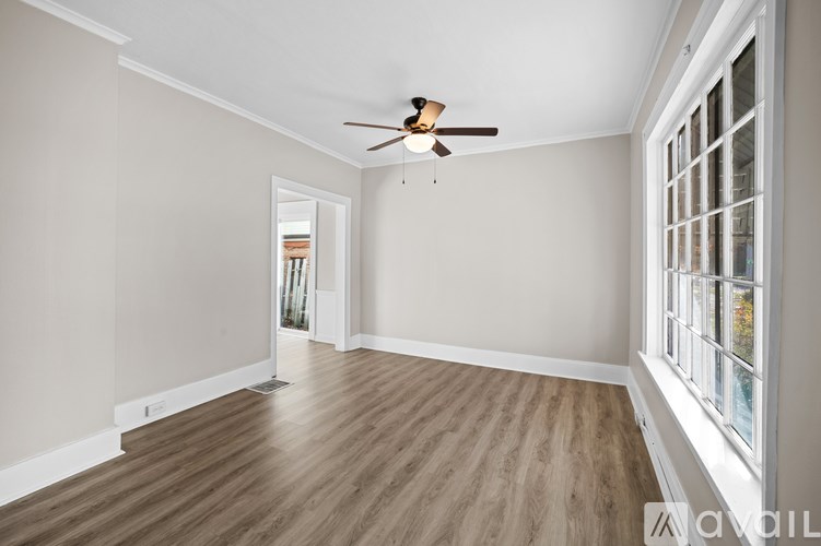 A room with a ceiling fan and wooden flooring.