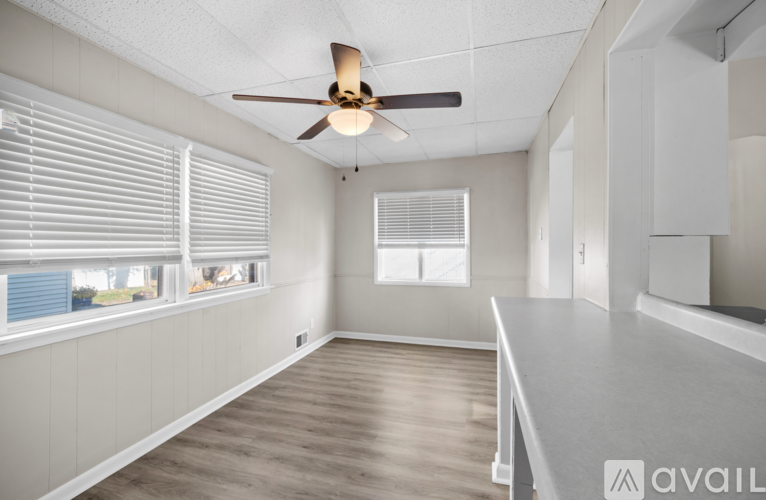 A spacious room with a ceiling fan and large windows.