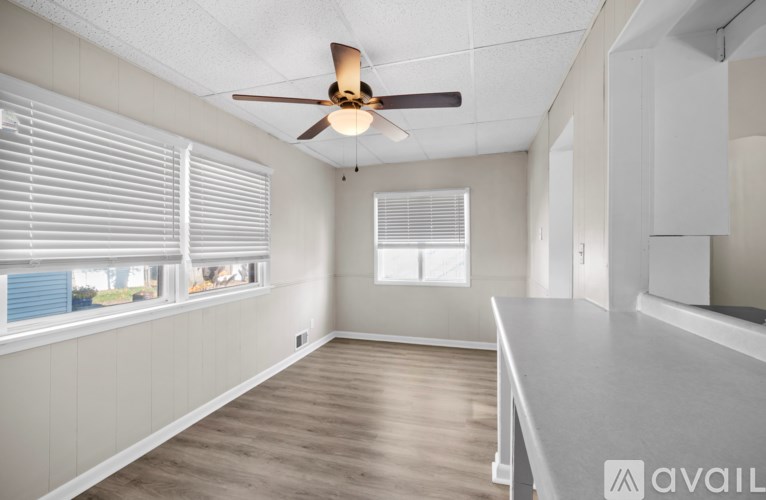 A spacious room with a ceiling fan and large windows.