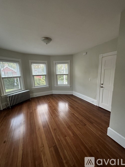 A room with wooden floors and three windows.