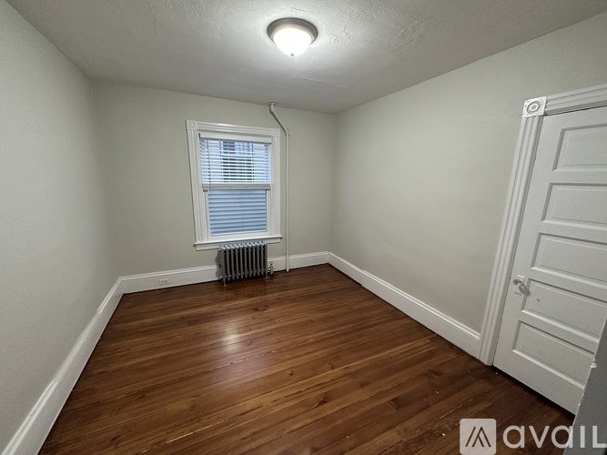 A room with wooden flooring and a window with blinds.