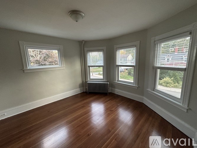 A room with wooden floors and three windows.