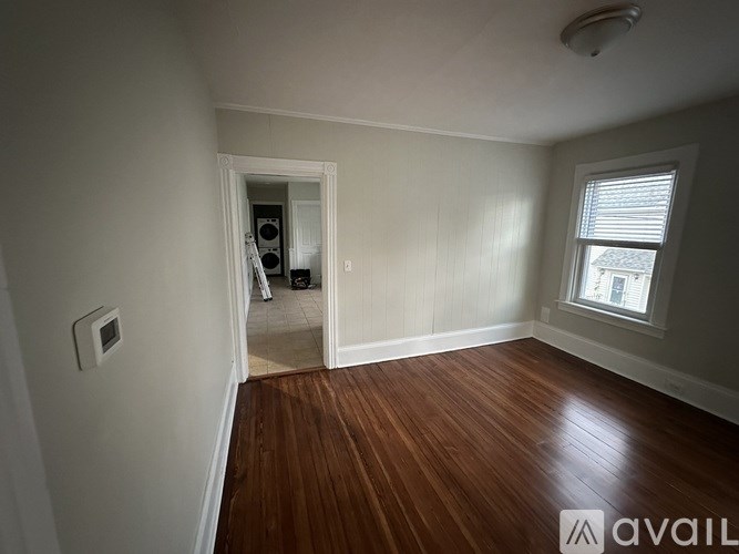 A room with wooden floors and a window with blinds.