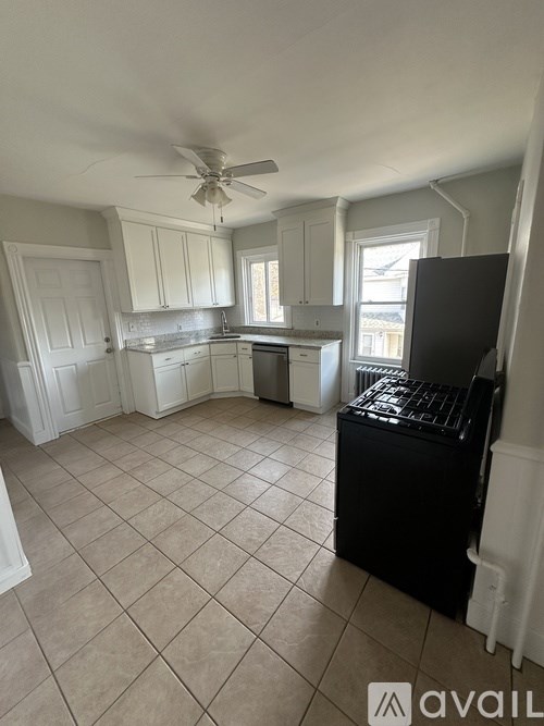 A kitchen with a black fridge and white cabinets.
