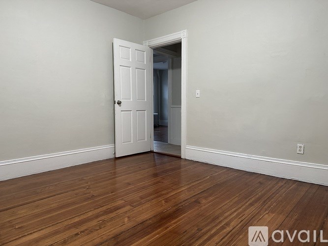 A room with a white door and wooden floor.