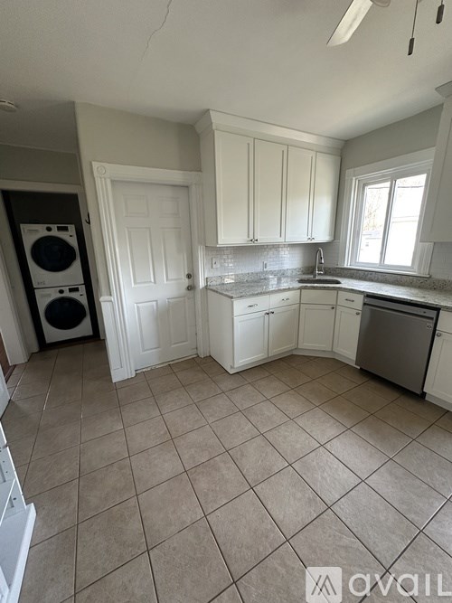 A kitchen with white cabinets and a washing machine.