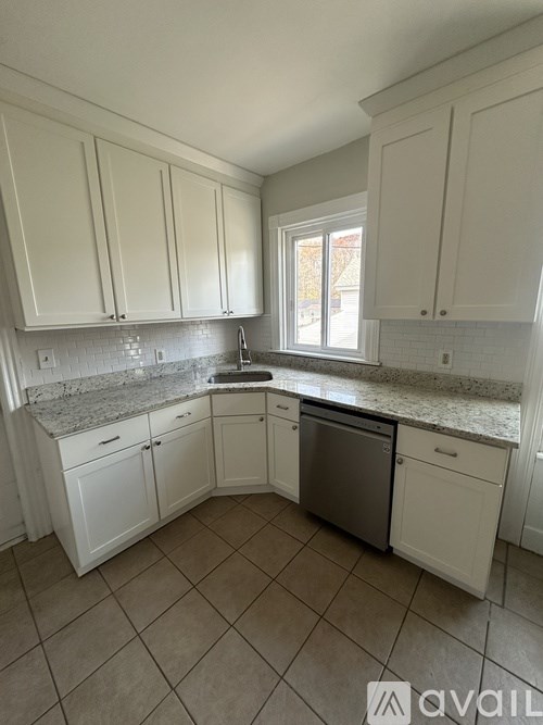 A kitchen with white cabinets and a marble countertop.