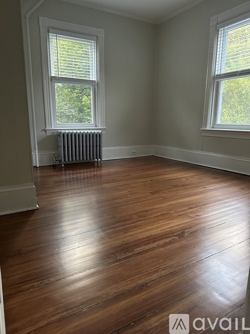 A room with wooden floors and two windows.
