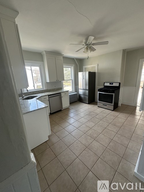 A kitchen with white cabinets and a fan on the ceiling.