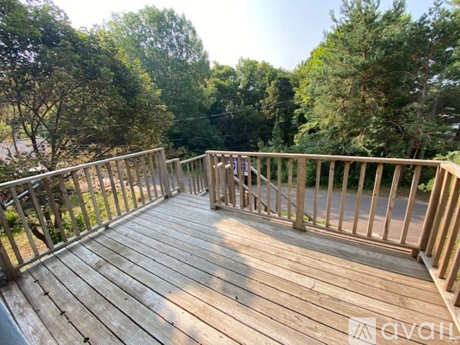 A wooden deck with a railing and trees in the background.