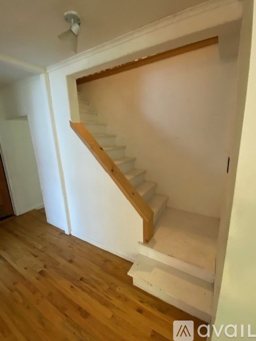 A wooden staircase with white steps and a wooden handrail.