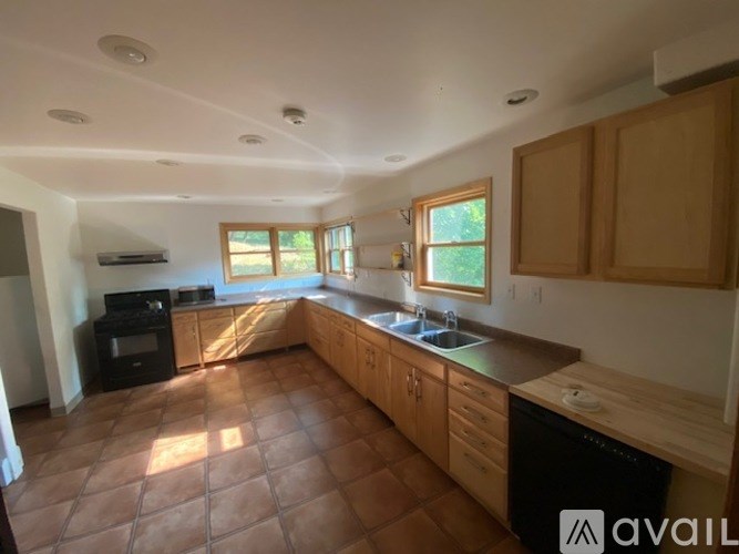 A kitchen with brown tile flooring and wooden cabinets.