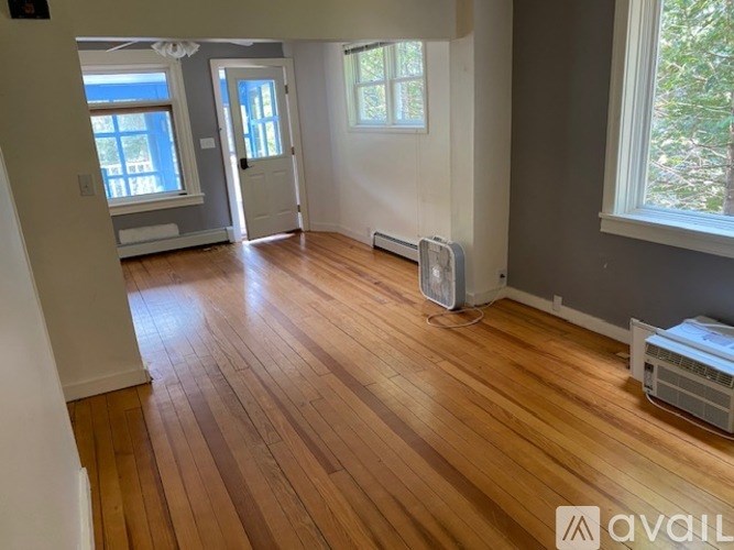 A room with wooden floors and a window with a view of trees.