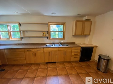 A room with wooden floors and a window with a view of trees.