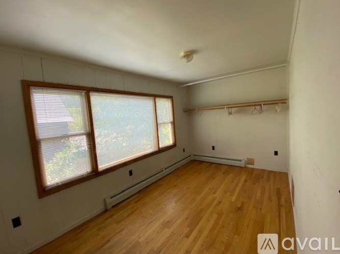 A room with wooden floors and a window with blinds.
