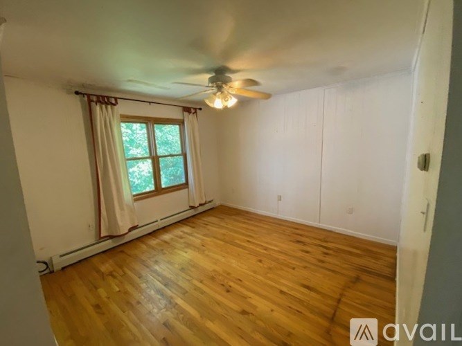 A room with wooden flooring and a window with curtains.