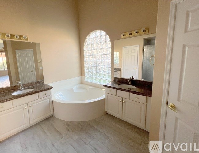 A bathroom with a large tub and double sinks.