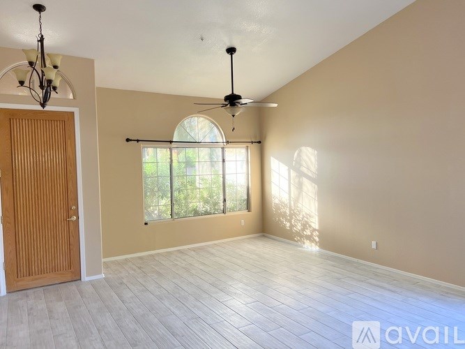 A room with a wooden door, a ceiling fan, and a window with blinds.