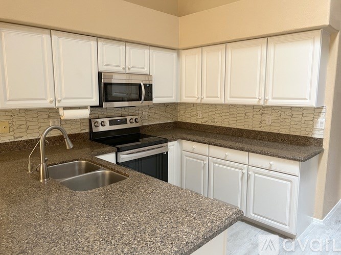 A kitchen with granite countertops and white cabinets.