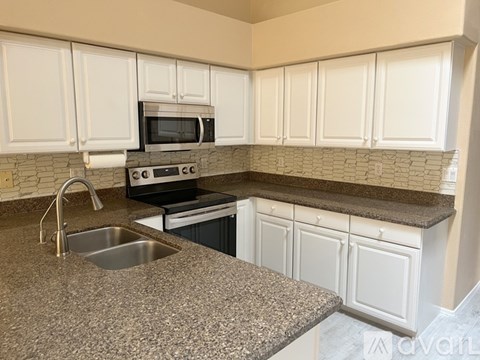 A kitchen with granite countertops and white cabinets.
