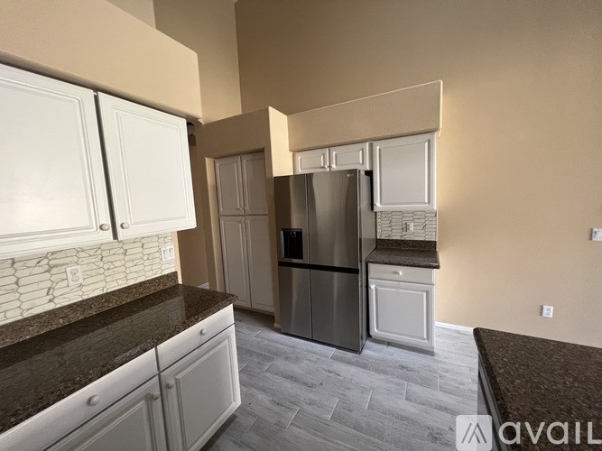 A kitchen with a refrigerator, cabinets, and a countertop.