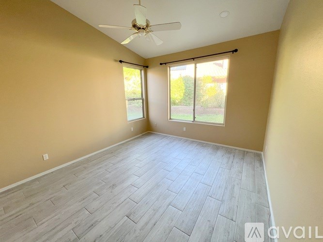 A room with a ceiling fan and sliding glass doors.