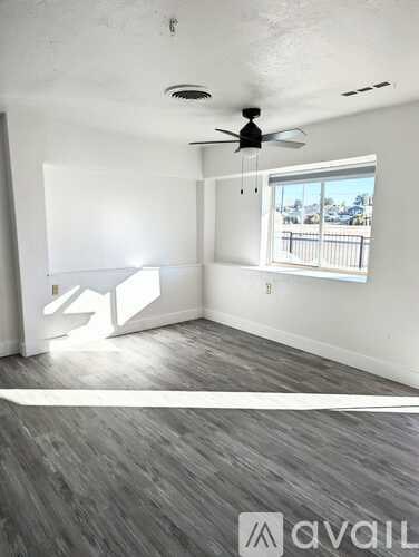 A room with a ceiling fan and a window overlooking a balcony.
