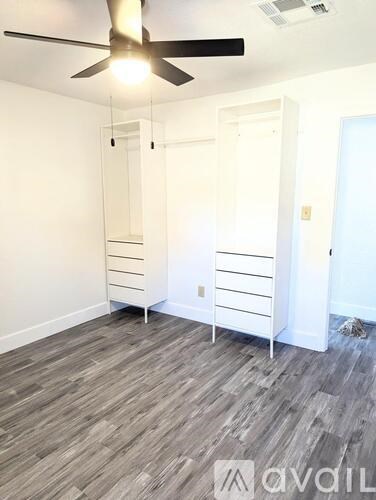 A room with a ceiling fan and a grey floor.